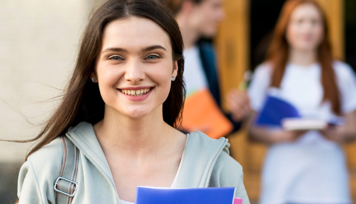 una ragazza sorridente con libri in mano